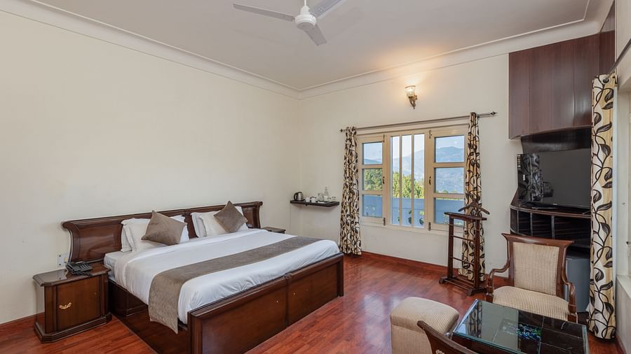  A well-lit bedroom with a fan, a comfortable bed, and warm lighting, creating a peaceful and relaxing environment with a scenic view of the outdoors.